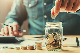 Zehnder_ALL_Sparen businessman holding coins putting in glass. concept saving money for finance accounting